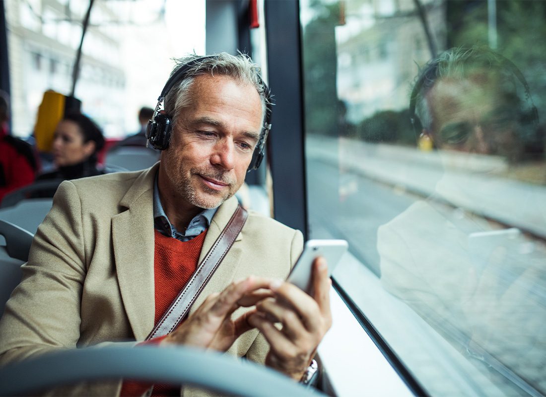Video Proposal - A Businessman Wearing a Pair of Headphones While Using His Smartphone and Riding the Bus in the City